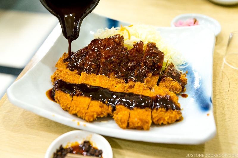 A plate containing Tonkatsu, shredded cabbage, and a small bowl of miso sauce.