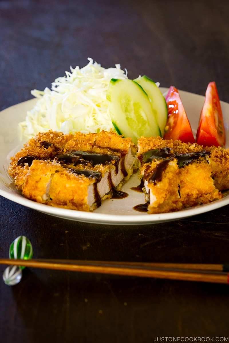 A plate containing Tonkatsu, Japanese pork cutlet, topped with Tonkatsu sauce.