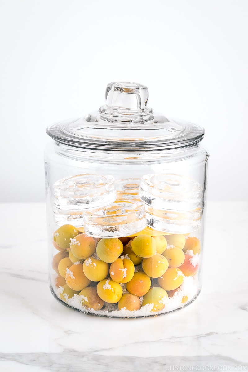 A glass container containing ume plums and salt.