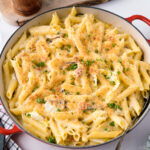 A red Le Creuset braiser containing creamy napa cabbage and bacon pasta.