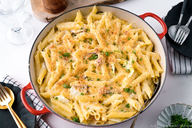 A red Le Creuset braiser containing creamy napa cabbage and bacon pasta.