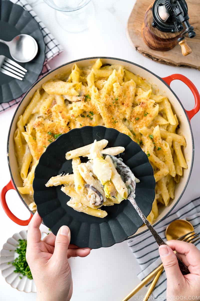 A red Le Creuset braiser containing creamy napa cabbage and bacon pasta.