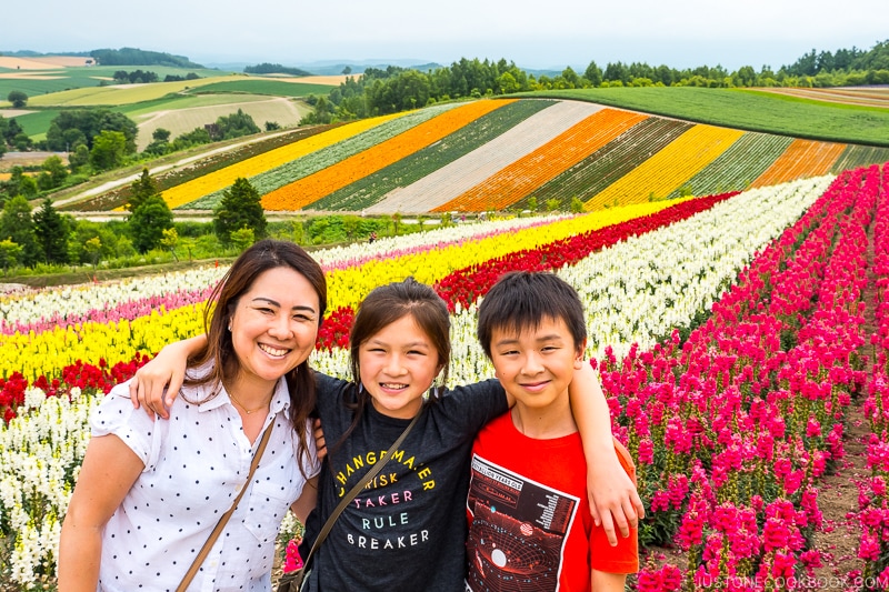 woman and two children in front of colorful flower fields