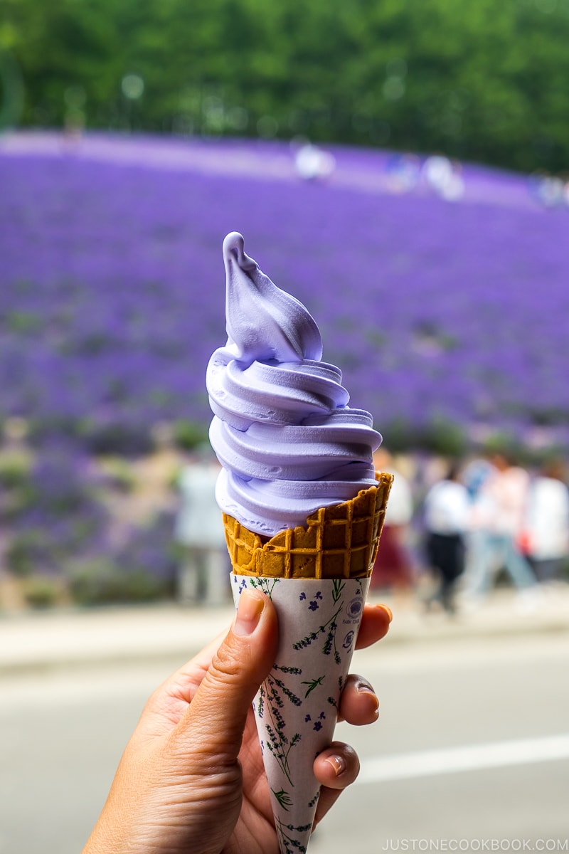 lavender ice cream on a cone in front of lavender field