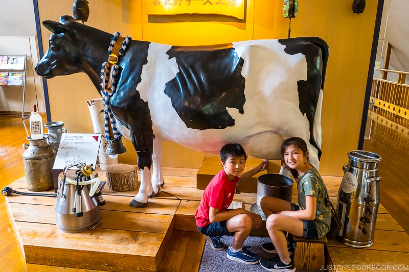 two children next to statue of a cow