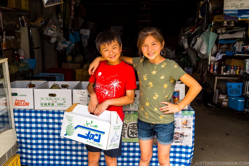 a boy and girl with boxes of Furano melon