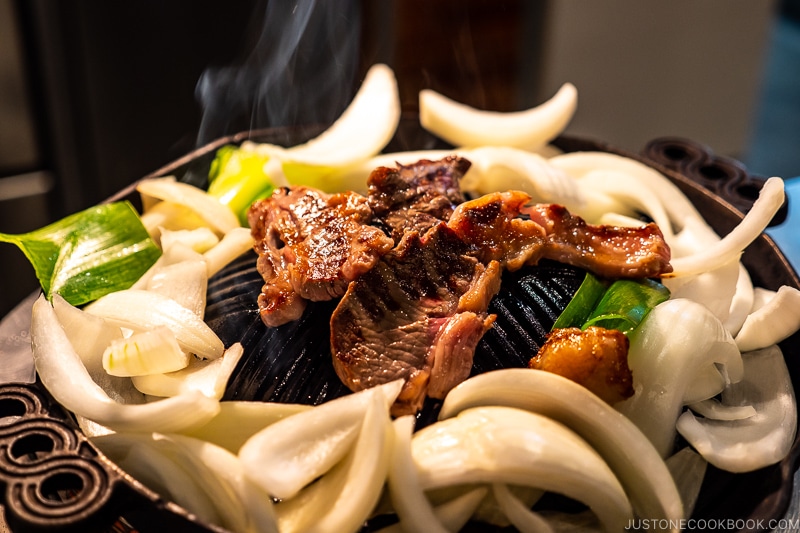 lamb and onions grilling on a metal grate