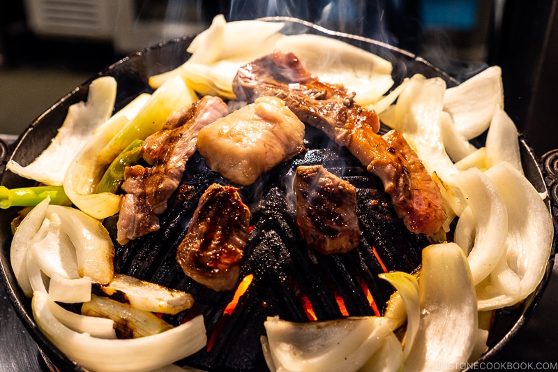 lamb and onions grilling on a metal grate