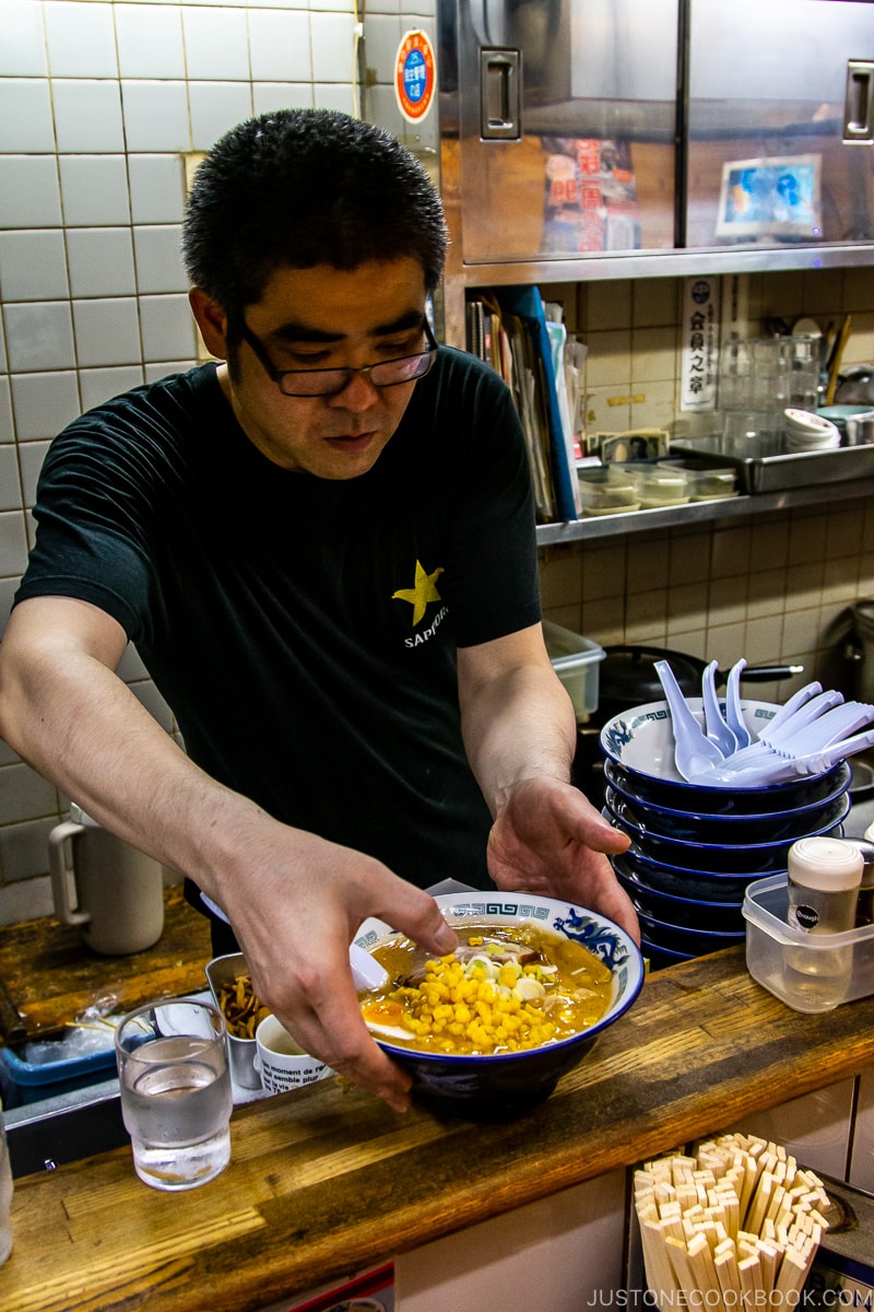 man serving ramen on counter