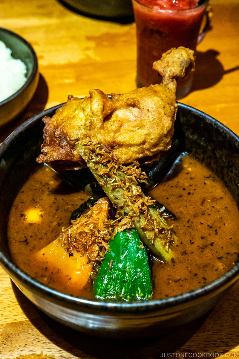 a bowl of soup curry with chicken on wood table