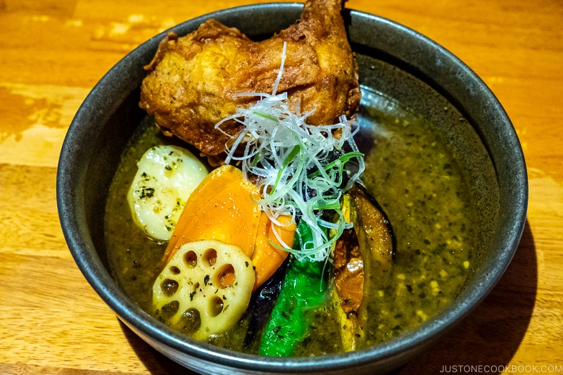 a bowl of soup curry with chicken on wood table