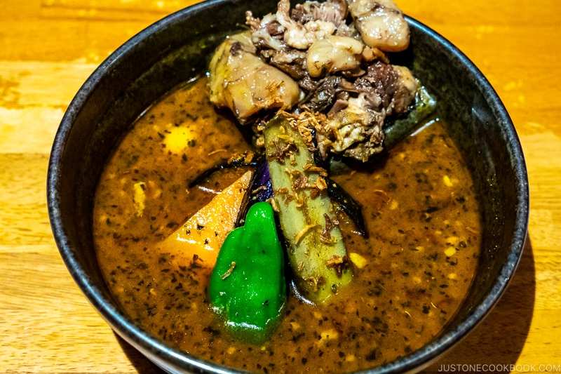 soup curry in a dark bowl on wood table