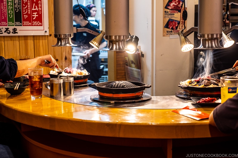 lamb being grilled by customers on metal grates