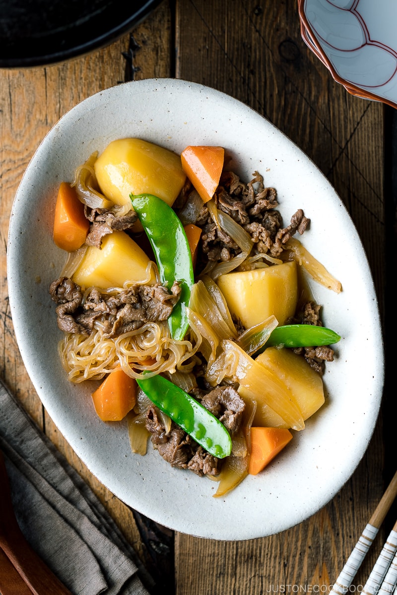 A white oval plate containing Nikujaga (Japanese Meat and Potato Stew).