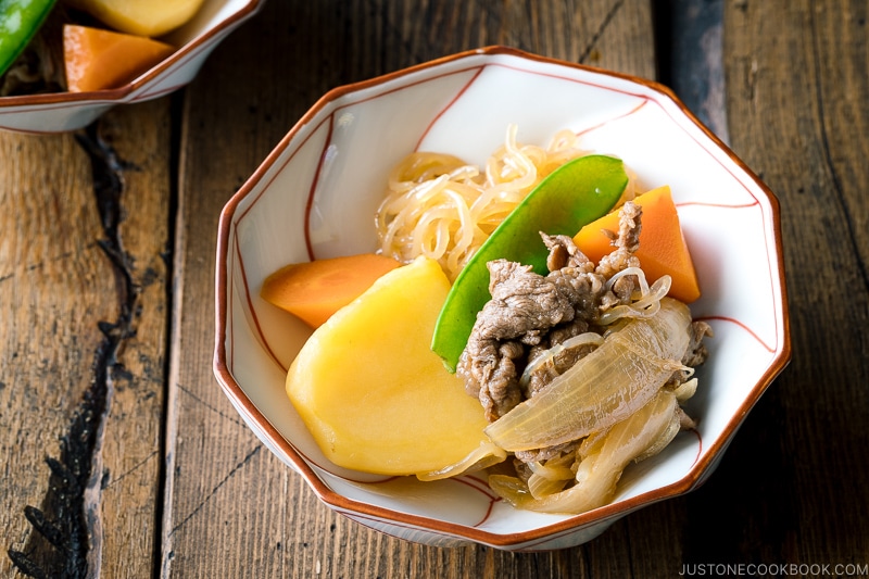 A white and red bowl containing Nikujaga (Japanese Meat and Potato Stew).