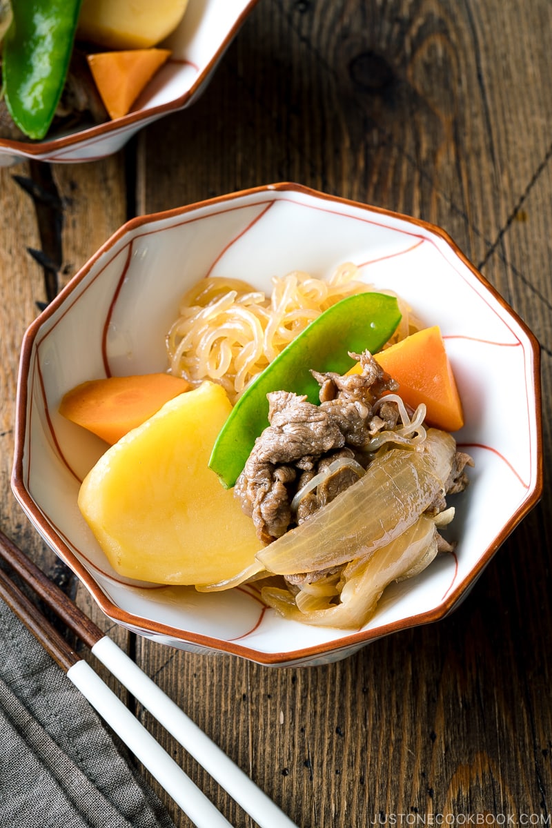 A white and red bowl containing Nikujaga (Japanese Meat and Potato Stew).