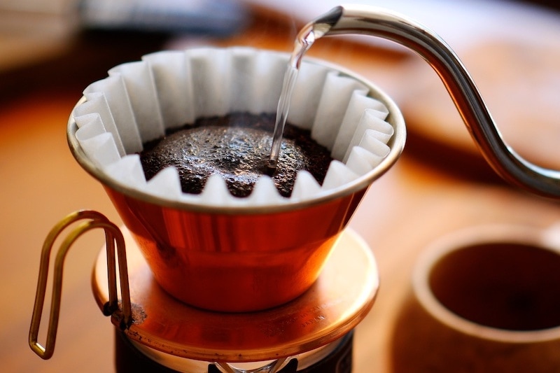 image of pouring hot coffee over charcoal roasted coffee in a coffee filter maker