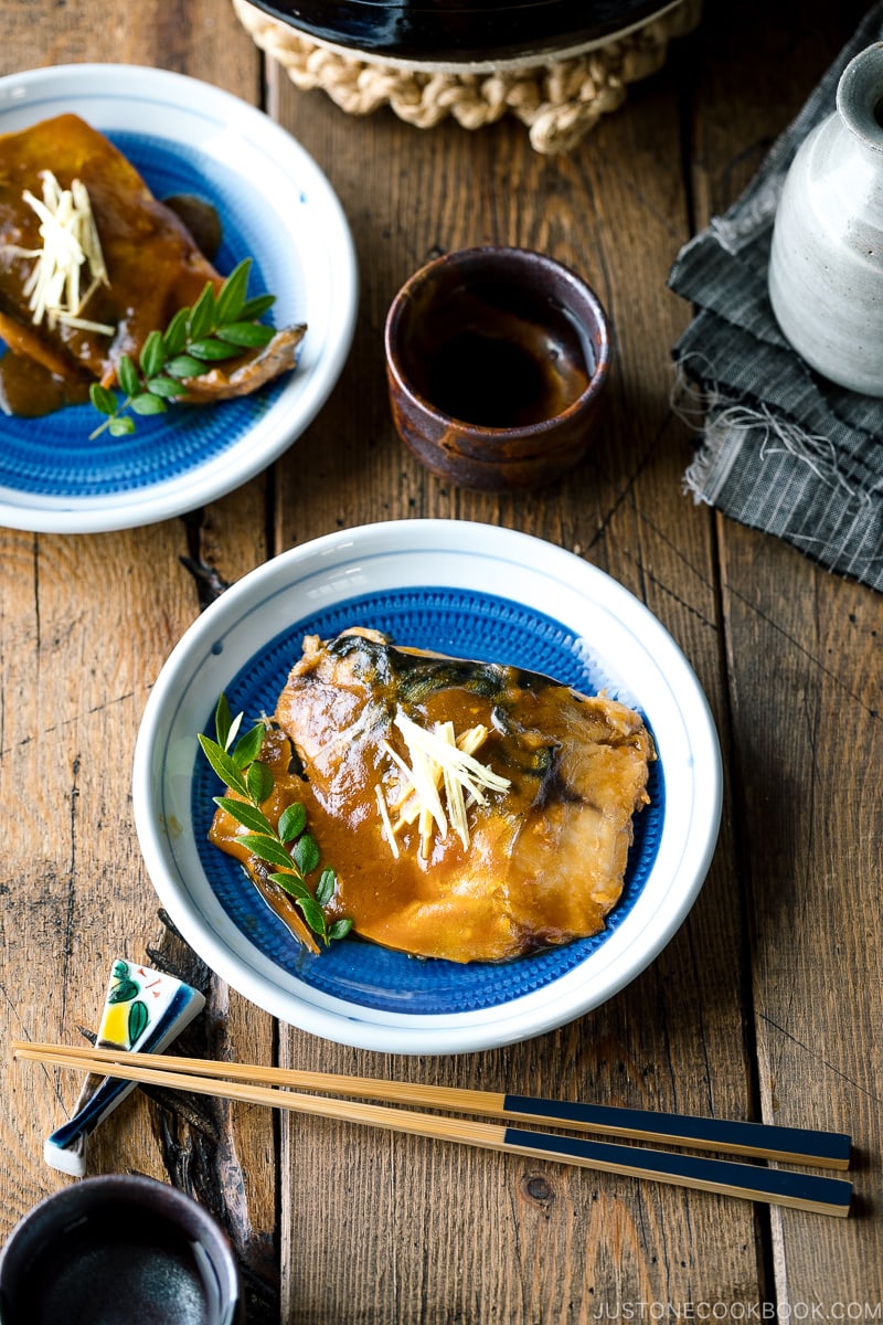 A blue Japanese plate containing Saba Misoni (Mackerel Simmered in Miso) garnished with julienned ginger.