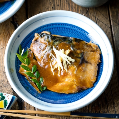 A blue Japanese plate containing Saba Misoni (Mackerel Simmered in Miso) garnished with julienned ginger.