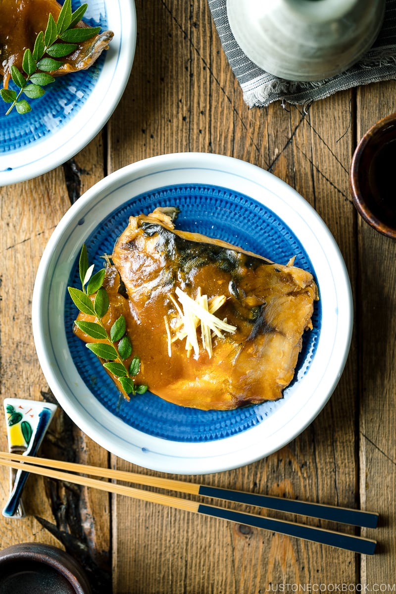 A blue Japanese plate containing Saba Misoni (Mackerel Simmered in Miso) garnished with julienned ginger.