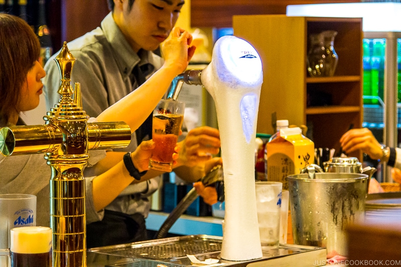 worker pour Asahi beer from tap