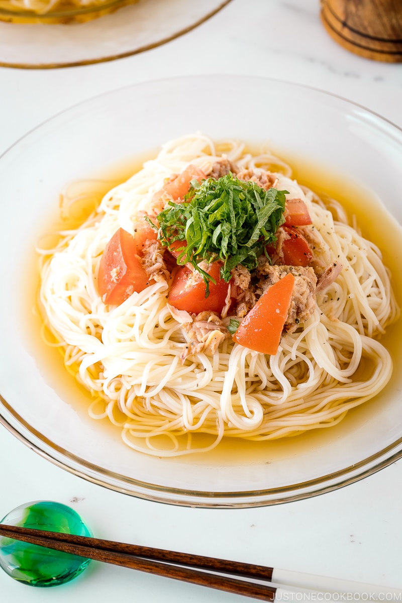 A glass plate containing Cold Tuna Tomato Somen topped with julienned shiso leaves.