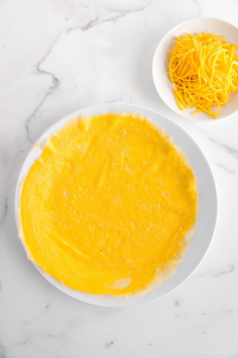 Plates containing thin egg crepe and thinly shredded egg crepe/omelette called Kinshi Tamago.