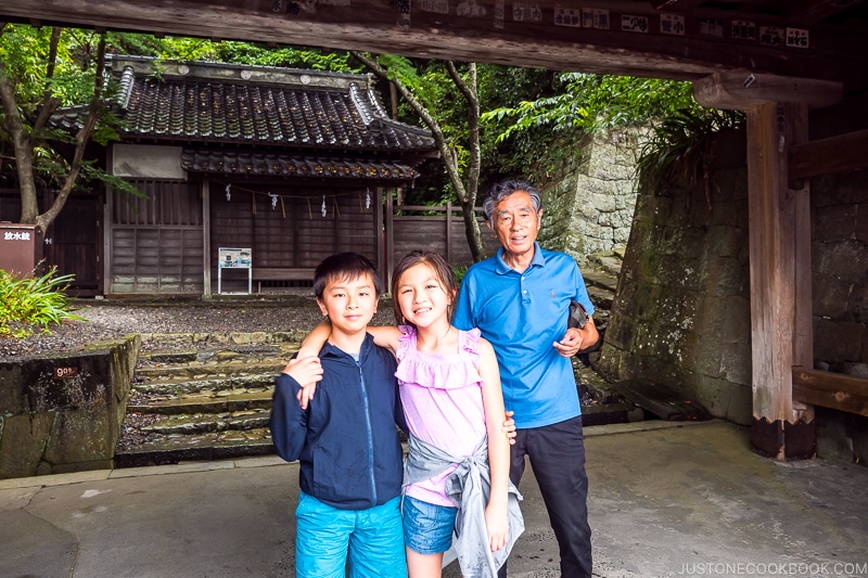 two children with an older man standing in front of a shrine structure