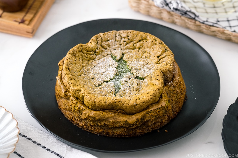 A black plate containing Matcha Gateau au Chocolat dusted with powdered sugar.