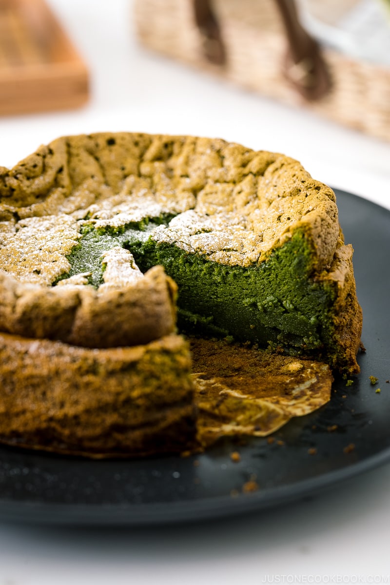 Une assiette noire contenant Matcha Gateau au Chocolat saupoudré de sucre en poudre.