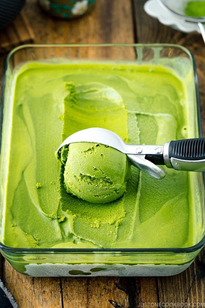 A glass container with matcha green tea ice cream in it.