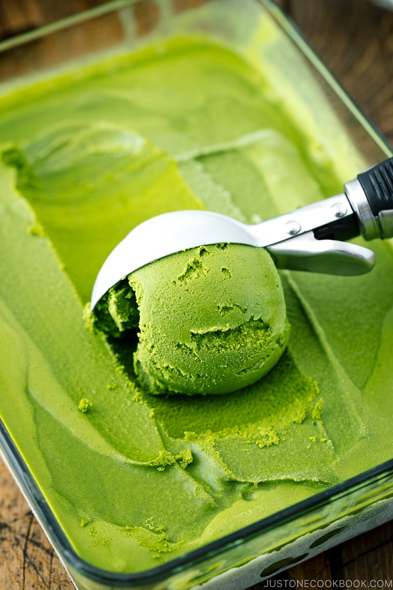 A glass container with matcha green tea ice cream in it.