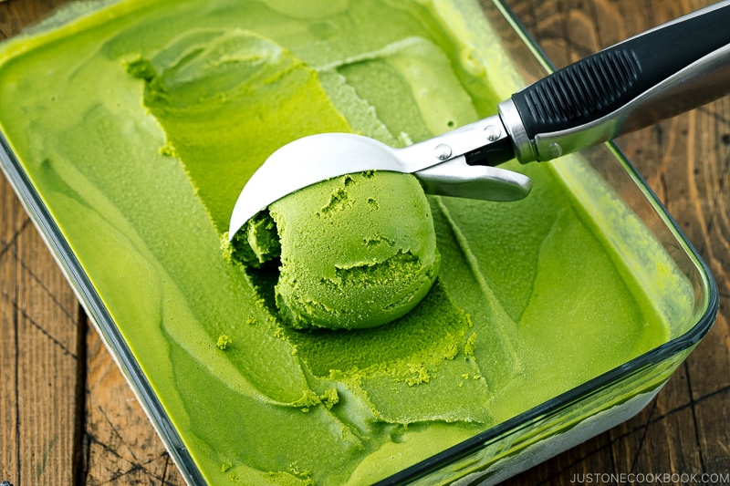 A Japanese kutaniware bowl containing matcha green tea ice cream served with a wooden spoon.