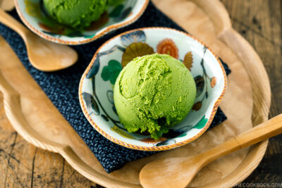 A Japanese kutaniware bowl containing matcha green tea ice cream served with wooden spoon.