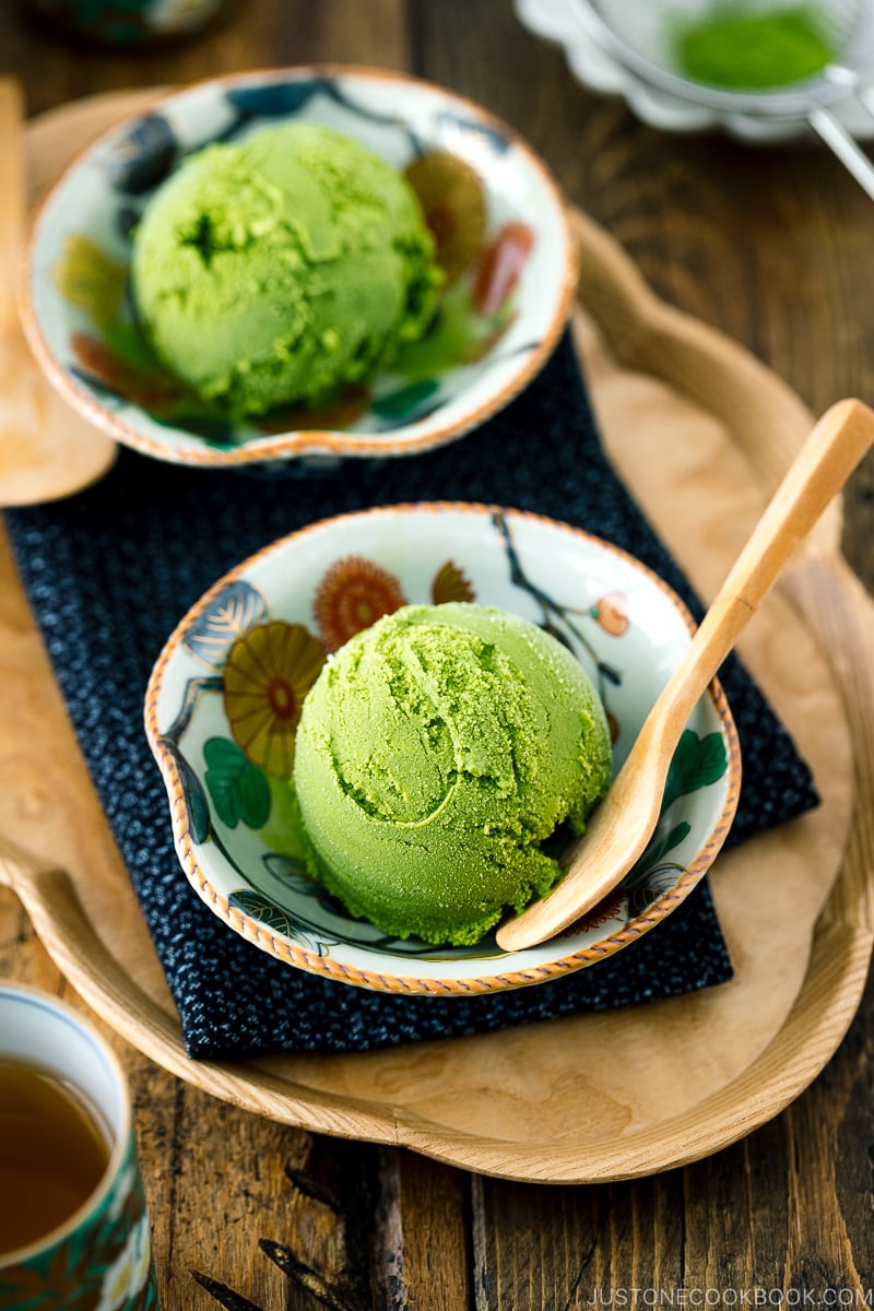 Un bol japonais kutaniware contenant de la glace au thé vert matcha servi avec une cuillère en bois.