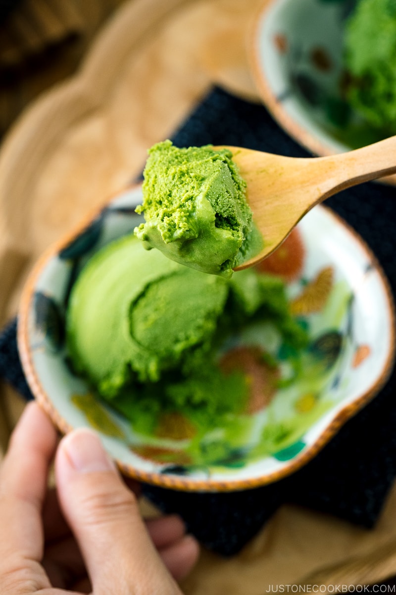 A Japanese kutaniware bowl containing matcha green tea ice cream served with wooden spoon.