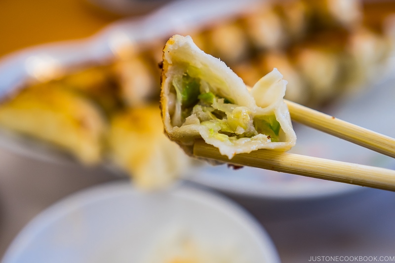 chopsticks holding a half eaten gyoza