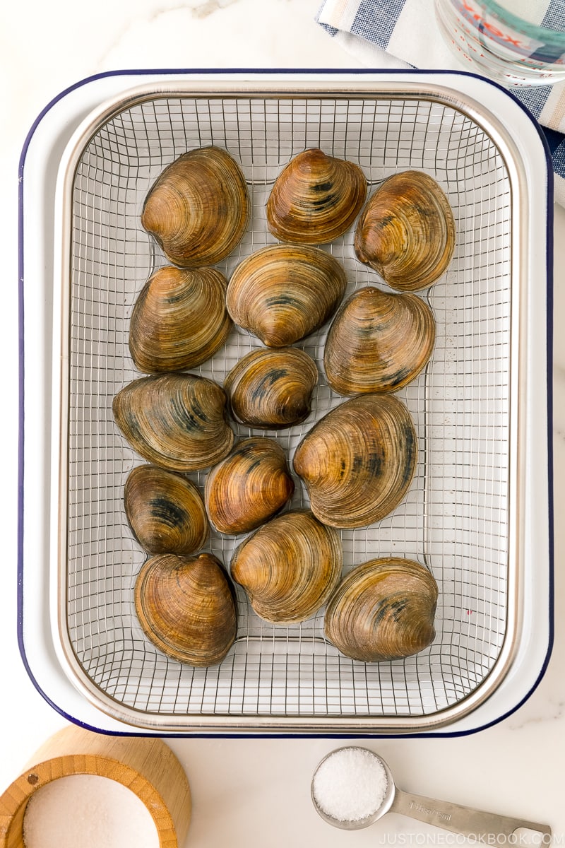 Clams being cleaned over a wire rack.