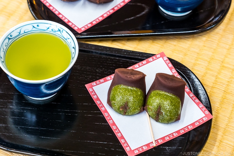 Fukutaro snacks on a paper plate next to a cup of green tea