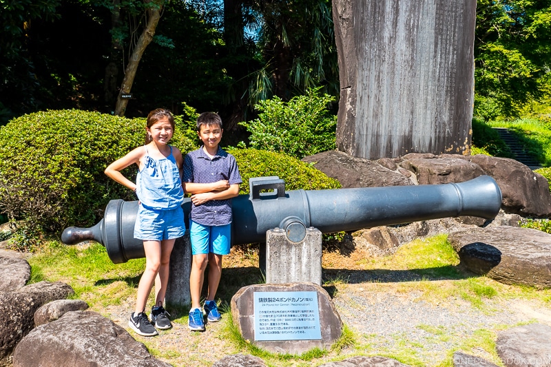 two children standing in front of a replica canon