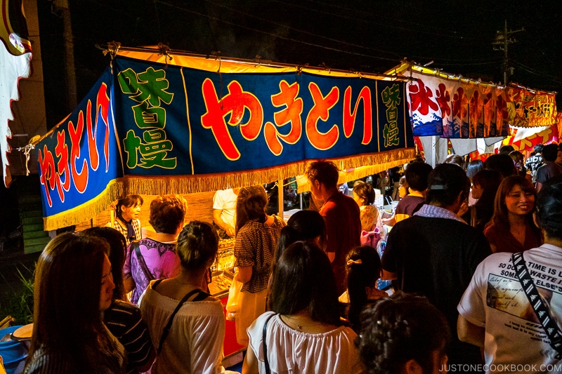 people walking along a riverbank festival at night