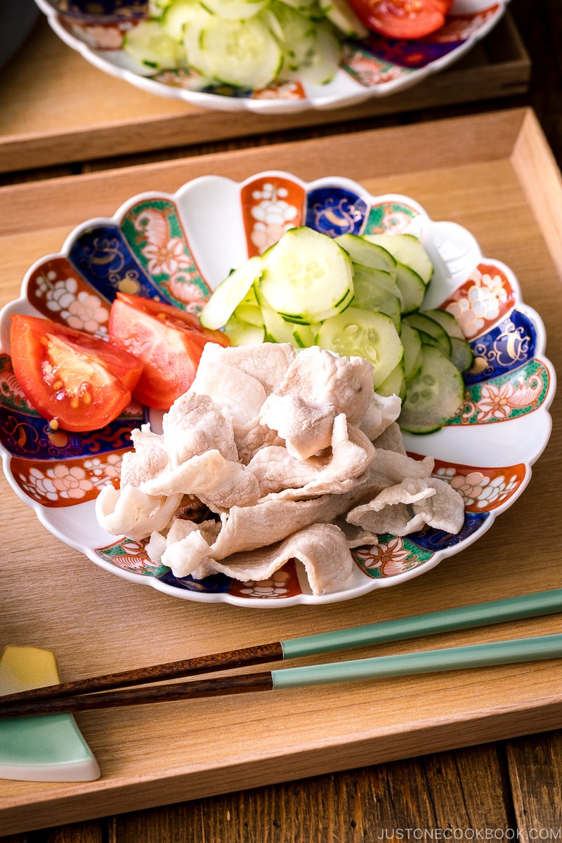 A plate containing pork shabu shabu and cucumber slices.
