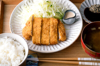 A Japanese ceramic containing Tonkatsu (pork cutlet) and shredded cabbage salad.