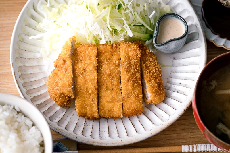 A Japanese ceramic containing Tonkatsu (pork cutlet) and shredded cabbage salad.