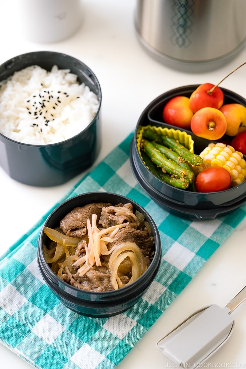 A Zojirushi lunch jar containing steamed rice, gyudon, fruits, and green bean gomaae.