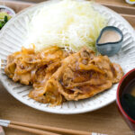 Ginger pork served with shredded cabbage on a white ceramic plate.