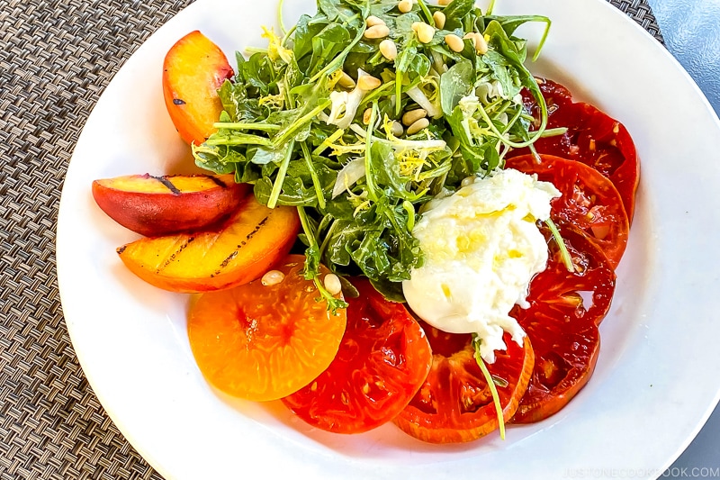 Heirloom Tomato Salad with grilled peach on a white plate