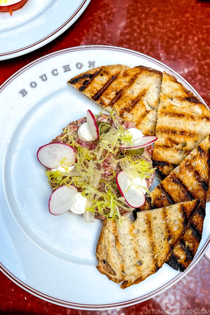 beef tartare on a white plate with grilled pain de campagne