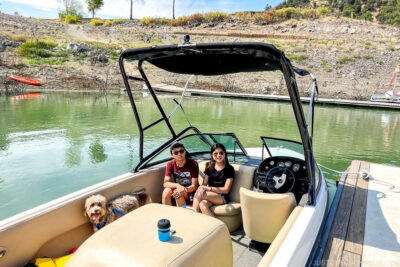 two children and a dog inside a boat on a lake