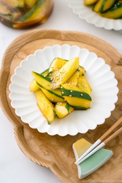 A white plate containing Spicy Japanese Pickled Cucumbers sprinkled with white sesame seeds.